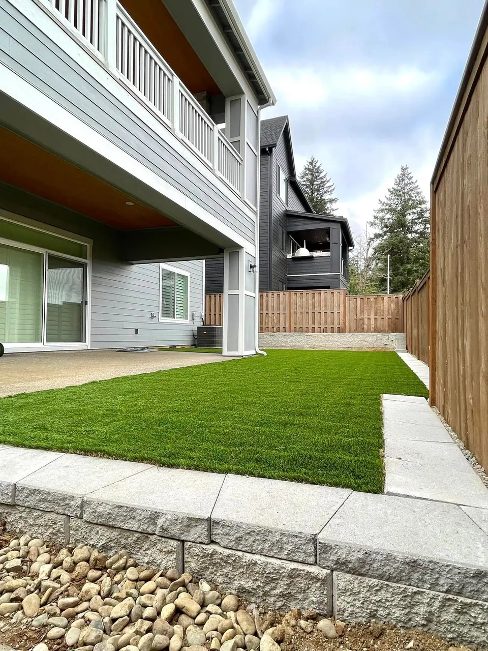 Artificial turf play area installed around a backyard playset