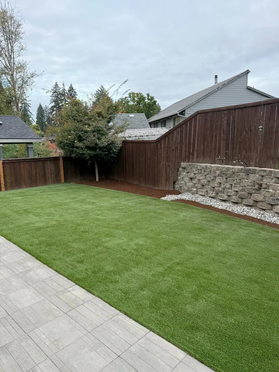 Artificial turf yard finished against a stone-filled retaining wall
