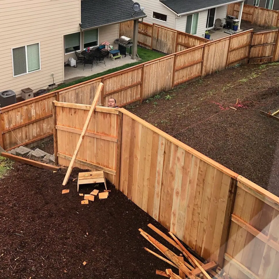 Cedar fence panels braced during installation with graded soil behind