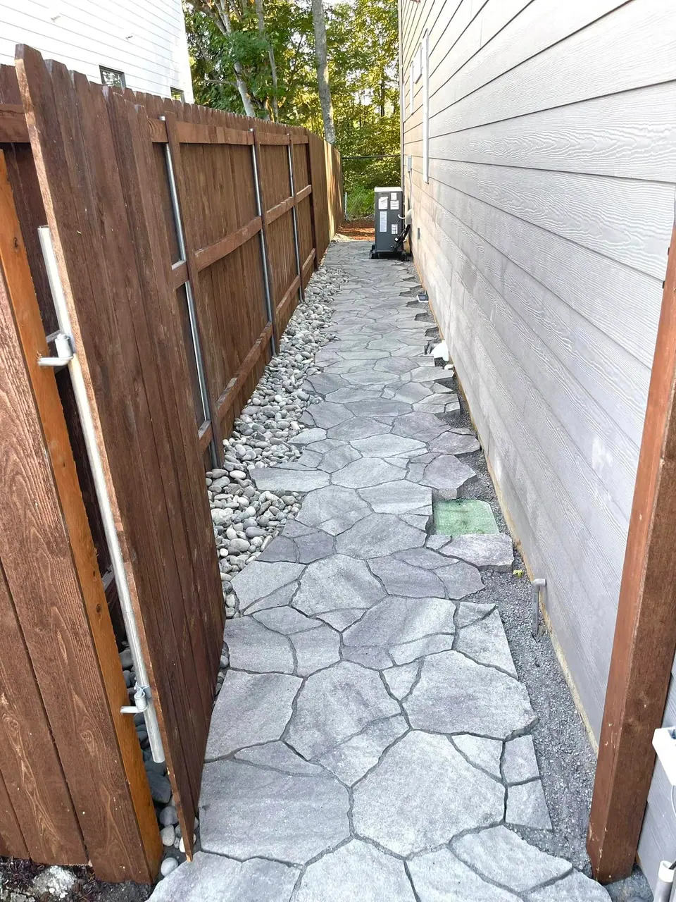 Flagstone stepping path set in river rock along a side yard