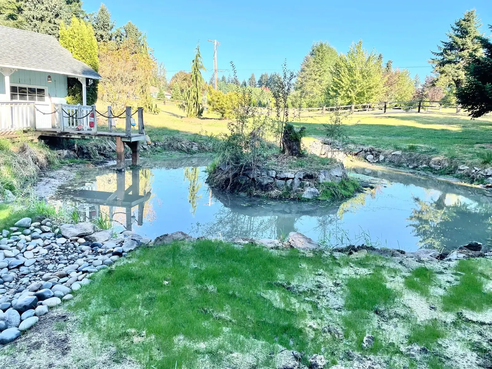 Large landscaped pond with surrounding lawn and mature trees