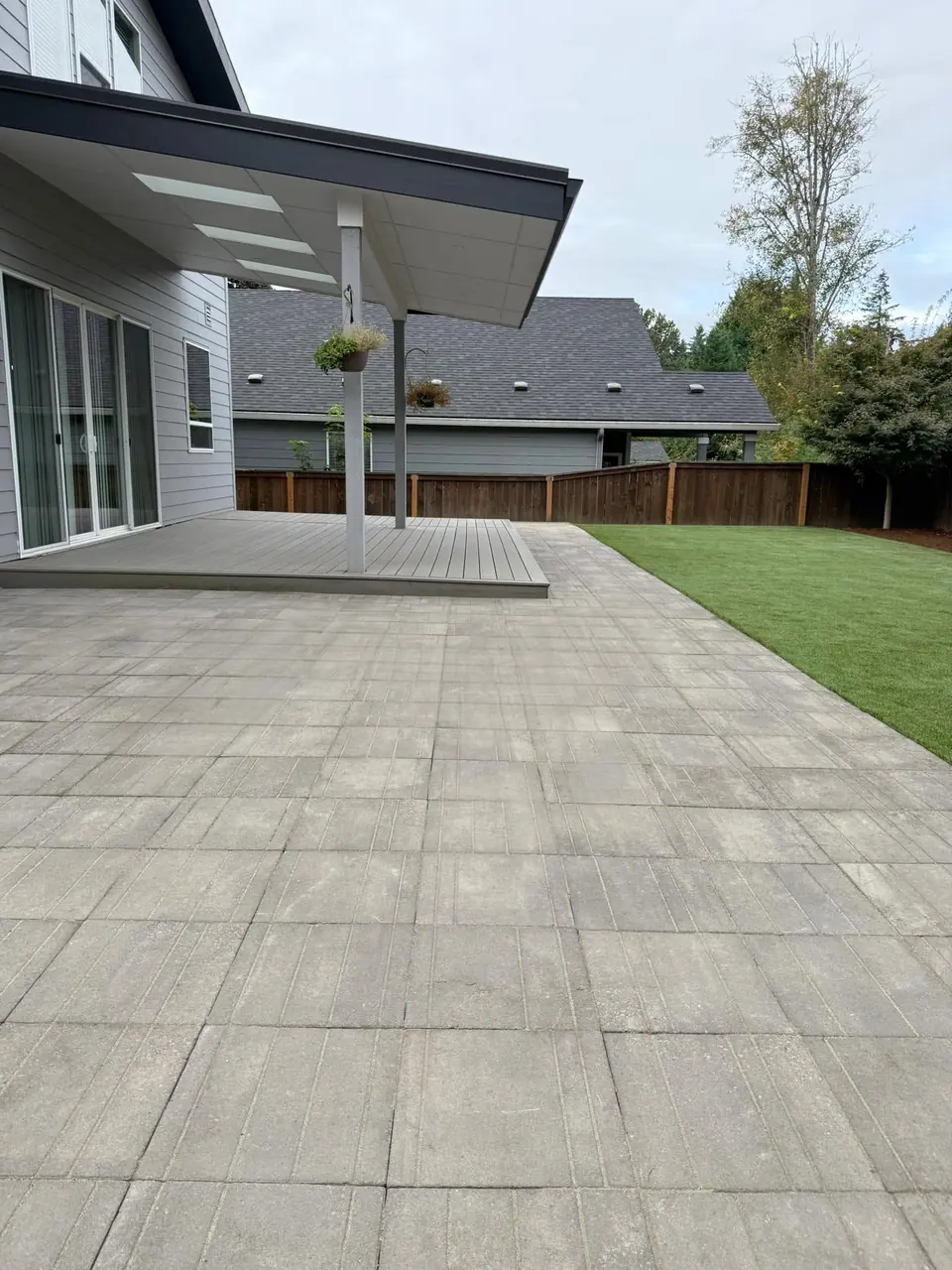 Modern grey paver patio meeting a manicured lawn