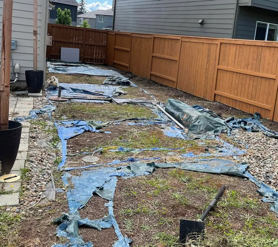 Old landscape plastic removed along a fence line during a drainage repair