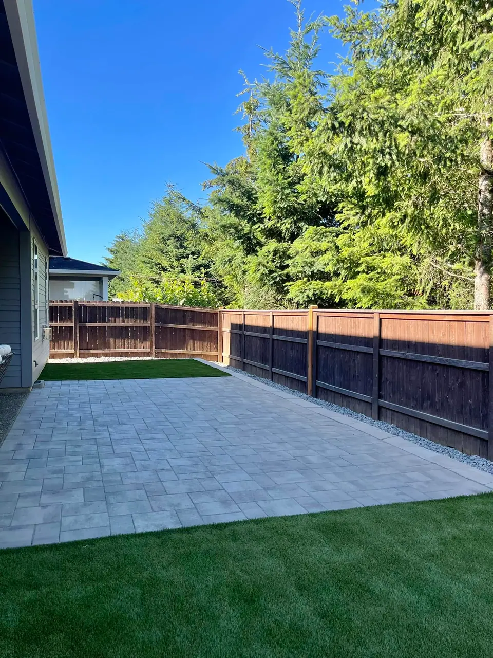 Paver patio meeting an artificial turf strip in a side yard